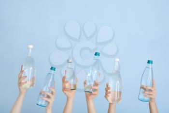 Female hands with bottles of water on color background�