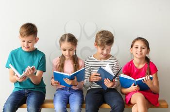 Cute little children reading books on grey background�