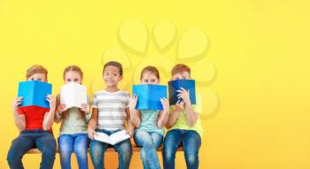 Cute little children with books on color background�