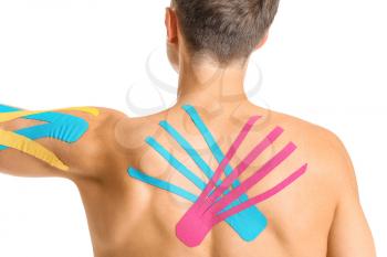 Sporty man with applied physio tape on body against white background�