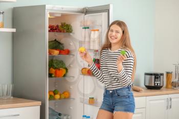 Woman taking food out of fridge at home�