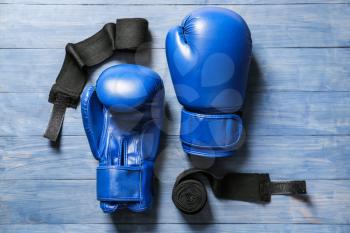 Boxing gloves and wrist bands on wooden background�
