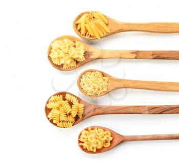 Spoons with different uncooked pasta on white background�
