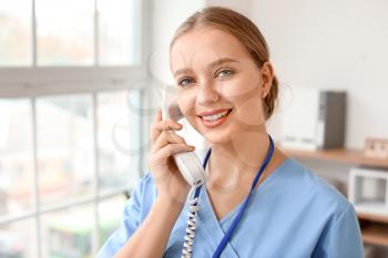 Young female receptionist talking by telephone in clinic�