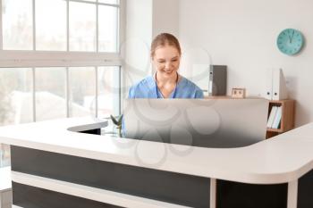 Young female receptionist working at desk in clinic�