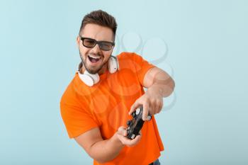 Young man playing video game on color background�