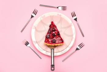 Plate with piece of tasty cherry pie and forks on color background�