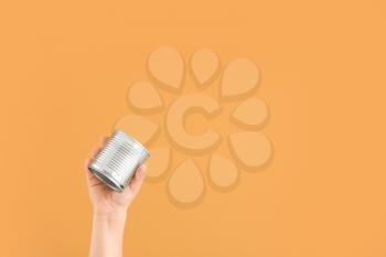 Hand with empty tin can on color background. Concept of recycling�