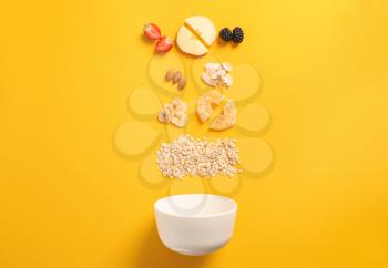 Bowl with tasty granola and ingredients on color background�
