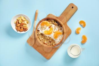 Tasty granola with yogurt in bowl on color background�