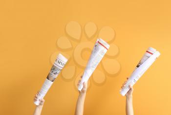 Female hands with newspapers on color background�
