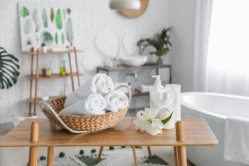 Clean towels with cosmetics on table in bathroom�