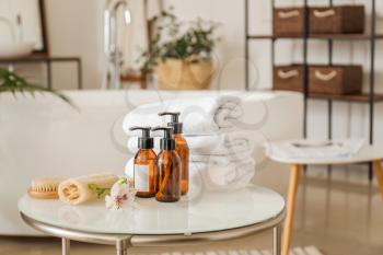 Clean towels with cosmetics and supplies on table in bathroom�