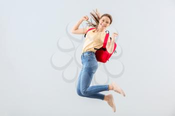 Jumping female student against light background�