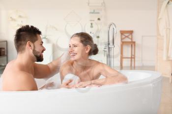 Happy young couple taking bath together�