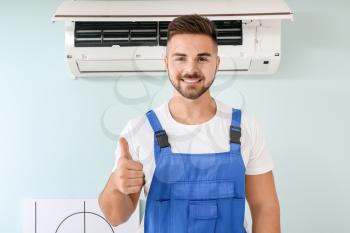 Male technician showing thumb-up after repairing air conditioner�