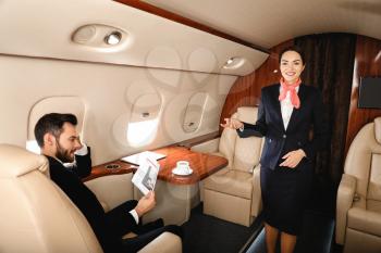 Air hostess and businessman on board the modern private airplane�