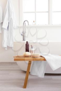 Body care cosmetics with accessories on bench in bathroom�