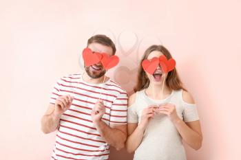 Happy young couple with red hearts on color background. Valentine's Day celebration�