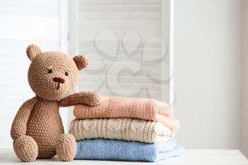 Stack of clean kid clothes with toy on table in room�