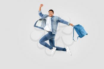 Jumping African-American teenager boy with backpack on white background�