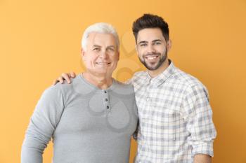 Young man and his father on color background�