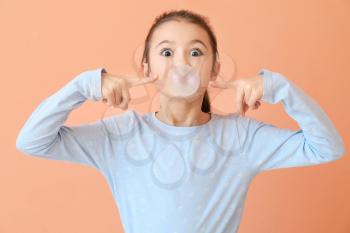 Cute little girl with chewing gum on color background�