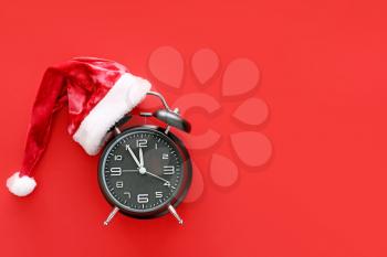 Alarm clock and Santa hat on color background. Christmas countdown concept�