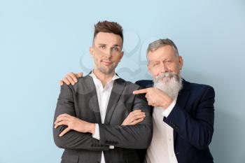 Portrait of senior man and his adult son on color background�