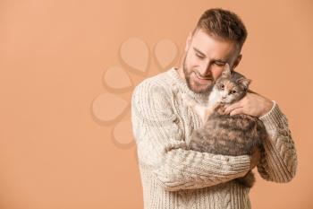 Man with cute cat on color background�