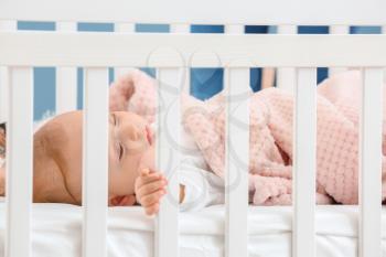Little baby sleeping in bed, view through railing�