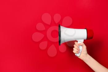 Female hand with megaphone on color background�