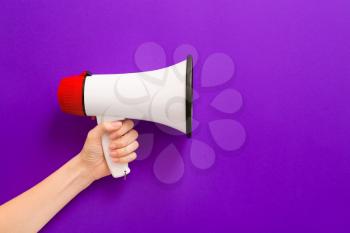 Female hand with megaphone on color background�