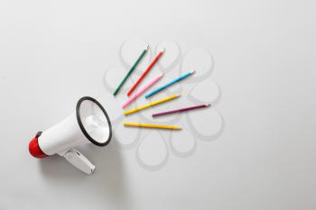 Megaphone with colorful pencils on white background�