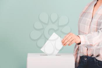 Voting woman near ballot box on color background�
