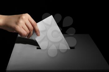 Voting woman near ballot box on dark background�