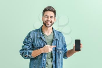 Happy young man with mobile phone on color background�