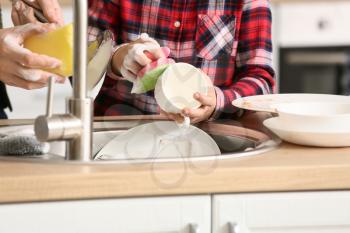 Father and son washing dishes in kitchen, closeup�