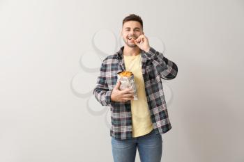 Handsome young man with tasty potato chips on light background�