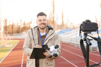 Male reporter with microphones at the stadium�