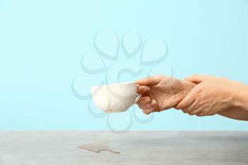 Woman suffering from Parkinson syndrome with cup of coffee against color background�
