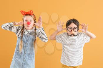 Little children in funny disguise on color background. April fools' day celebration�