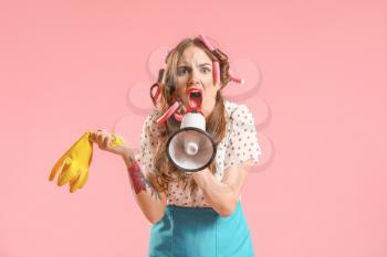 Funny housewife with megaphone on color background�