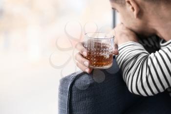 Depressed young man drinking alcohol at home�