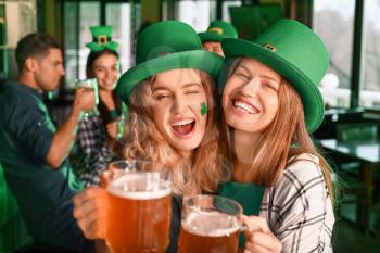 Young women with beer celebrating St. Patrick's Day in pub�
