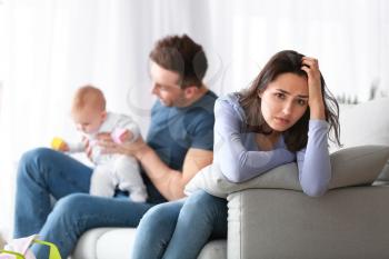 Happy father with his baby and wife suffering from postnatal depression at home�