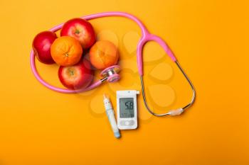 Digital glucometer, lancet pen, stethoscope and fruits on color background. Diabetes concept�
