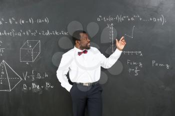 African-American math teacher near blackboard in classroom�