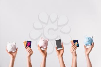 Female hands with credit cards, piggy banks and mobile phone on light background. Concept of online banking�