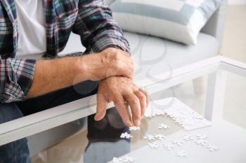 Senior man with Parkinson syndrome doing puzzle at home�